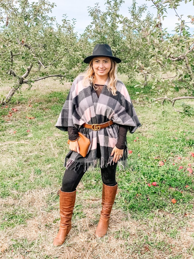 Fall outfits at the orchards wearing a poncho, boots, and fall hat