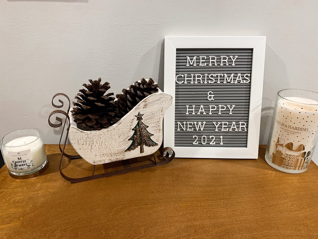 Pine cones in a decorative sleigh and letter board as Christmas decor