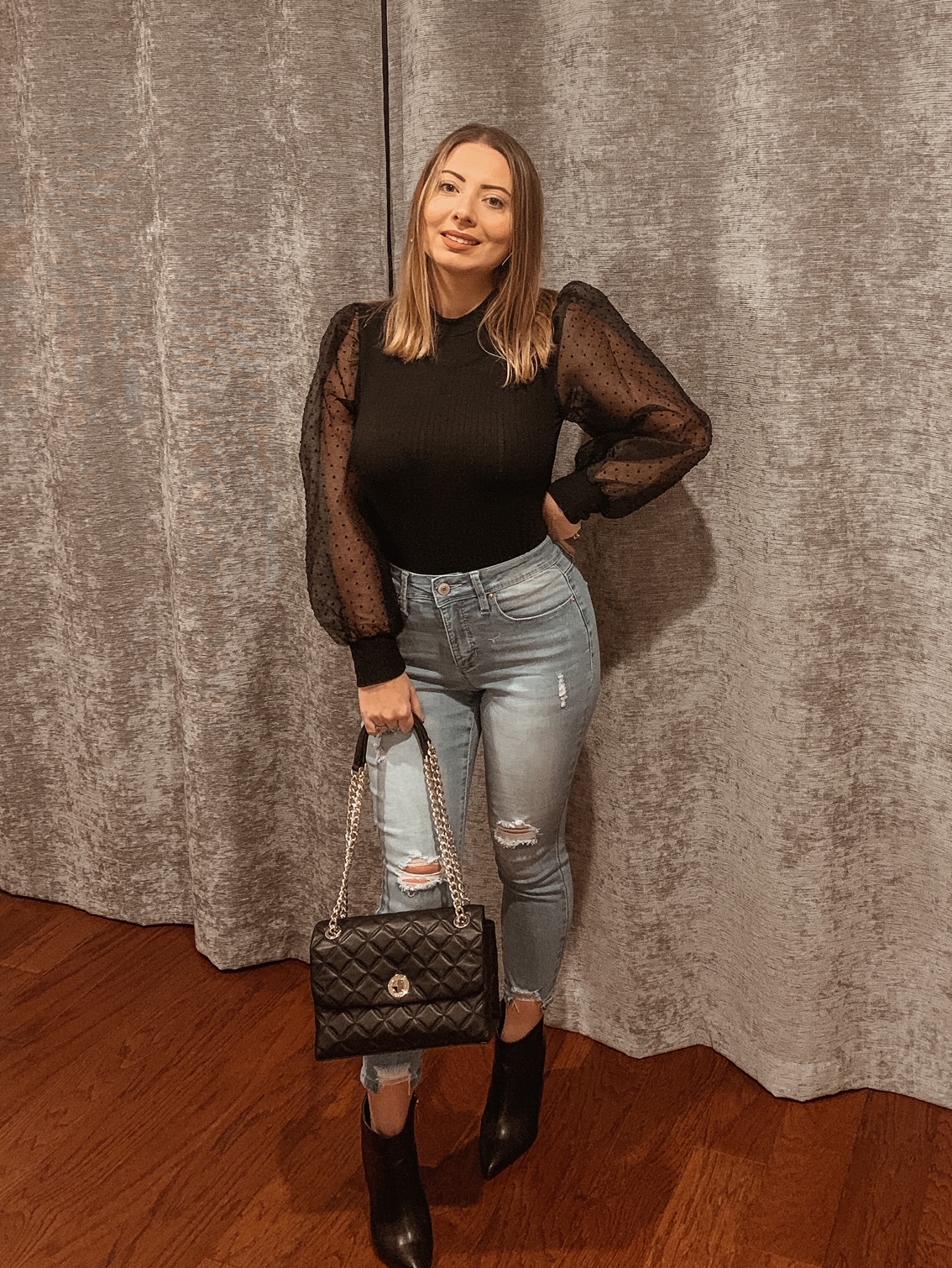 black balloon puff sleeve shirt styled with blue jeans and black booties