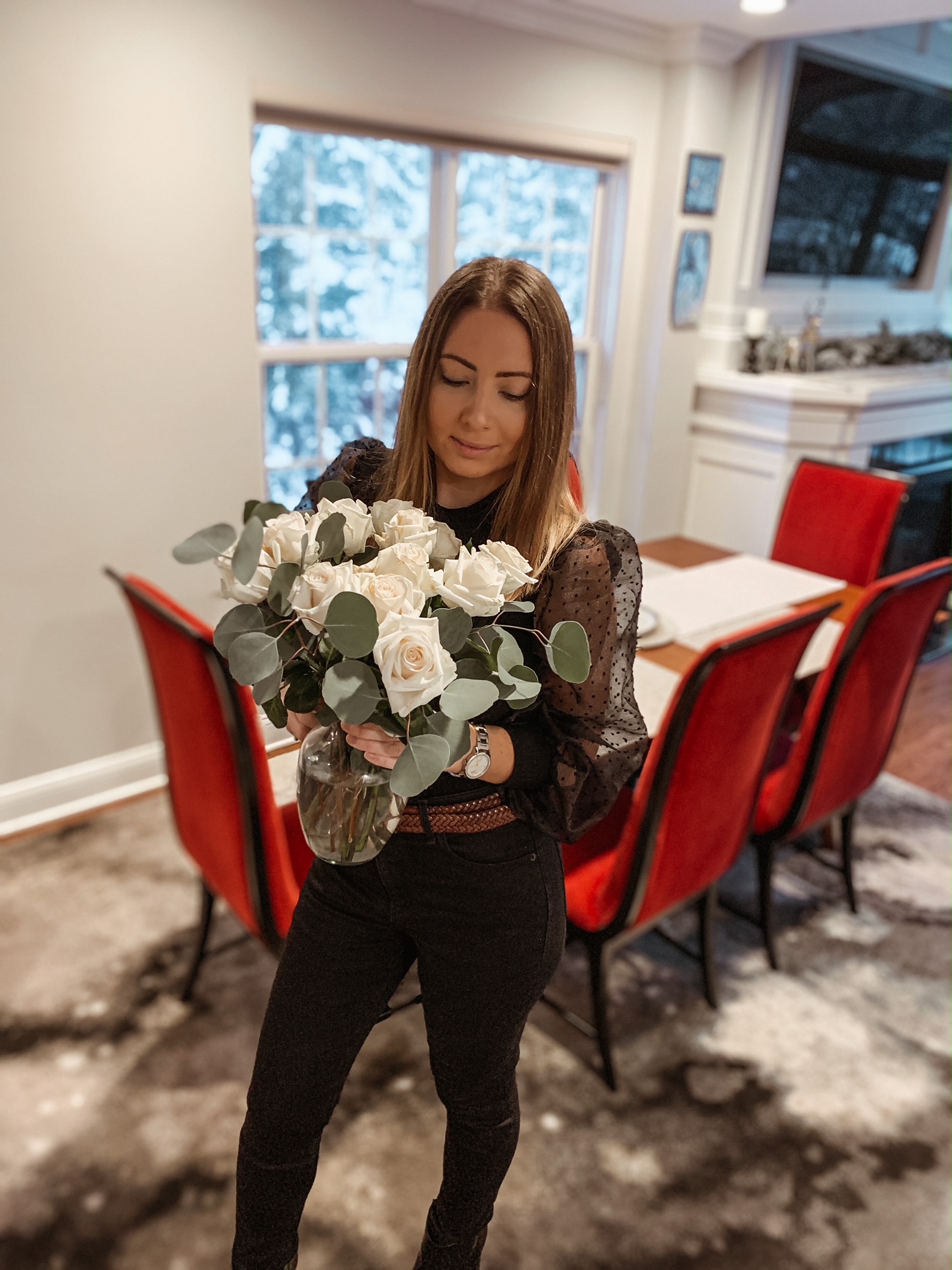 Holding white roses wearing a black balloon puff sleeve shirt and black jeans