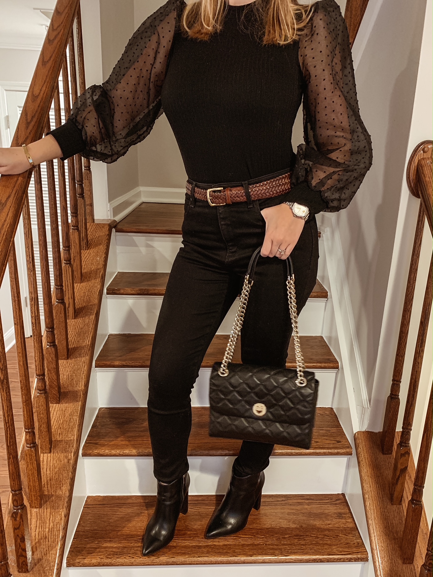 Black balloon puff sleeve top with black jeans, black Kate Spade handbag, Movado watch and dark brown belt